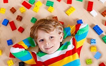 Boy lying on the floor in colorful striped shirt lying on Lego
